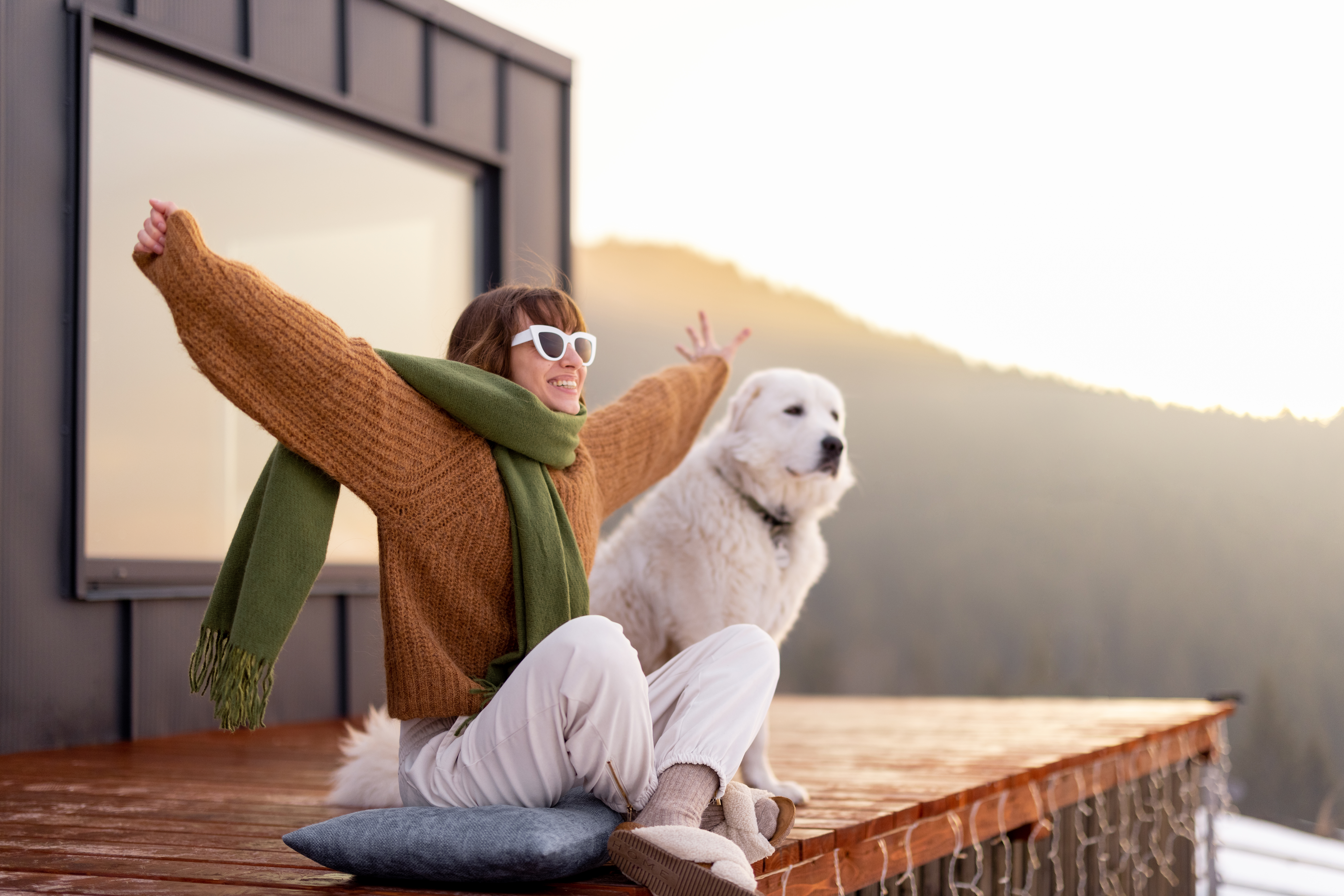 Woman with her dog resting on terrace of tiny house on nature
