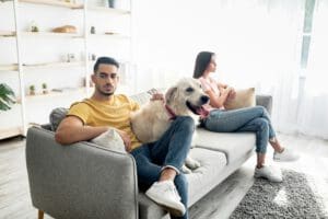 Upset young Arab man hugging pet dog after conflict with his girlfriend at home